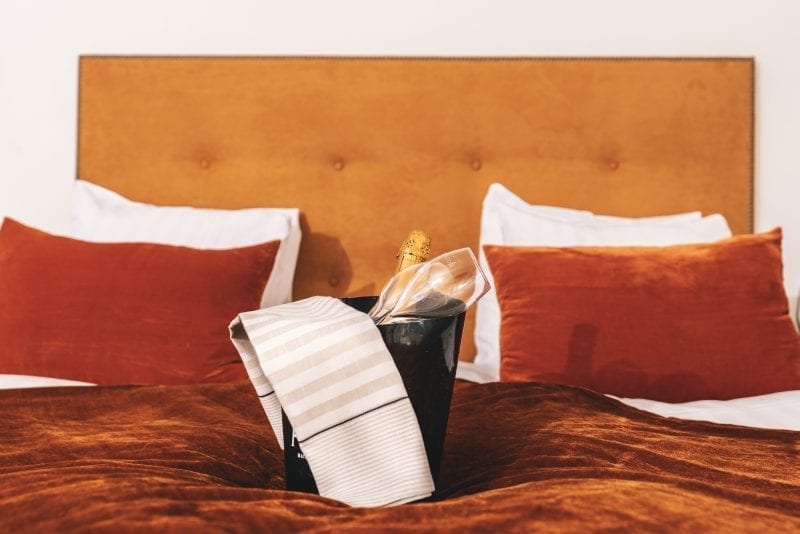 en säng med kuddar och en flaska champagne på kylning